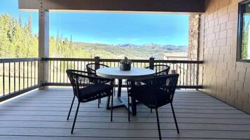Une terrasse extérieure couverte, avec une table ronde et quatre chaises, offrant une vue sur un paysage montagneux.