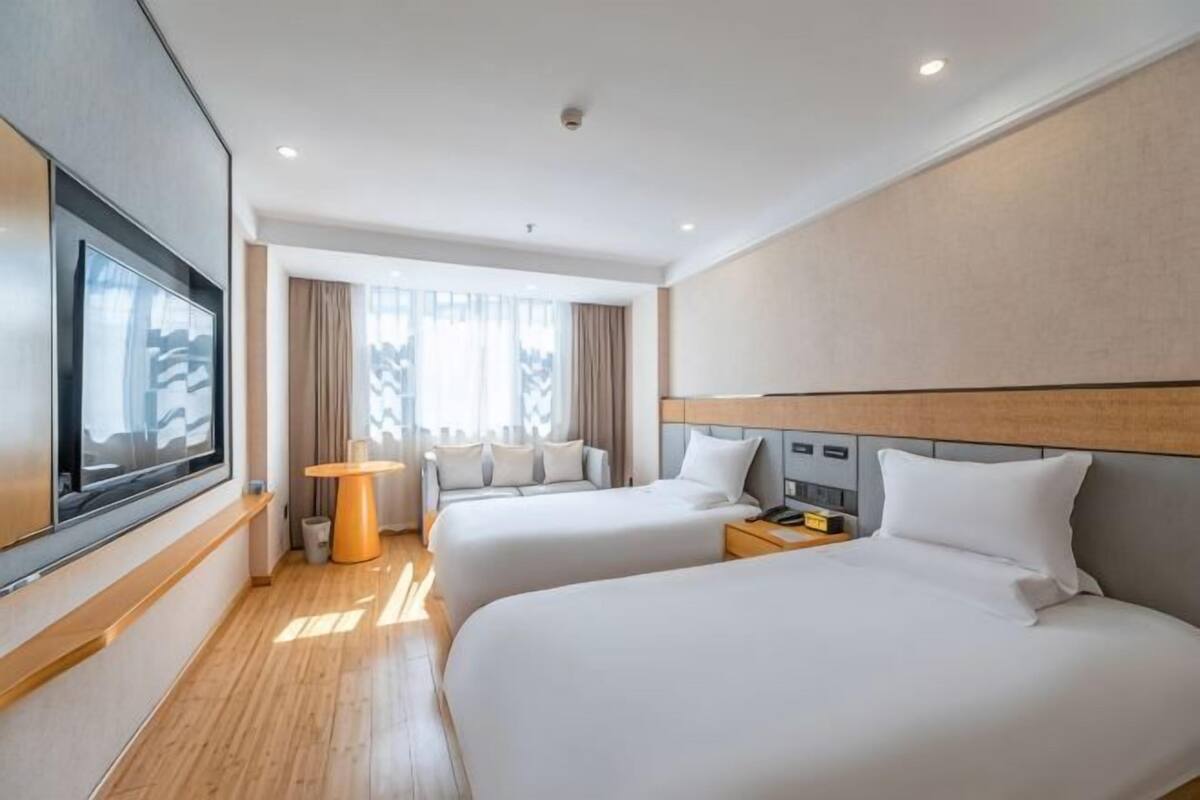 Ein Hotelzimmer mit zwei Betten, einem Fernseher, einem Schreibtisch und einer Lampe.
