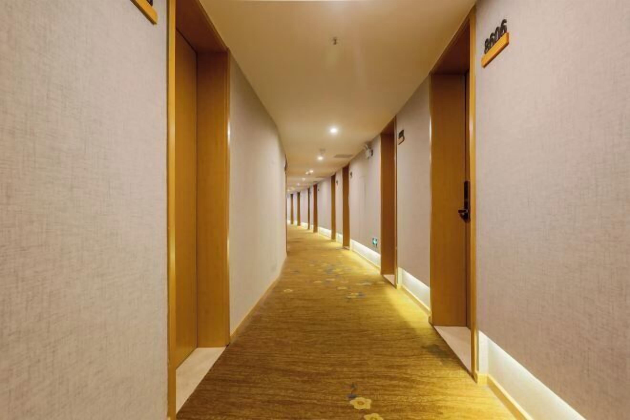 Un pasillo de hotel con piso alfombrado, puertas de madera y un letrero que indica la habitación 8606.