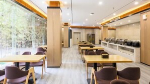 A modern dining area with wooden tables and chairs, a glass wall with a view, and a buffet counter. - HUAZHU-StarwayHotel (Shangrao Central Plaza Pedestrian Street store) (Shangrao)
