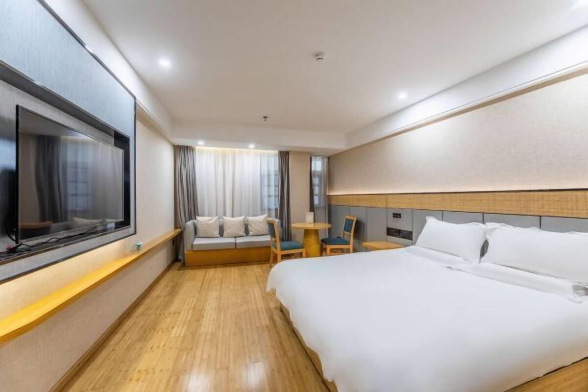 Ein Hotelzimmer mit einem Bett, einem Fernseher, einer Sitzecke mit Sofa und Sesseln sowie einem kleinen Tisch.
