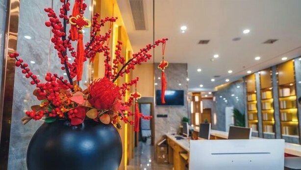 A modern hotel lobby with a large black vase of red flowers on a marble table. - HUAZHU-StarwayHotel (Shangrao Central Plaza Pedestrian Street store) (Shangrao)