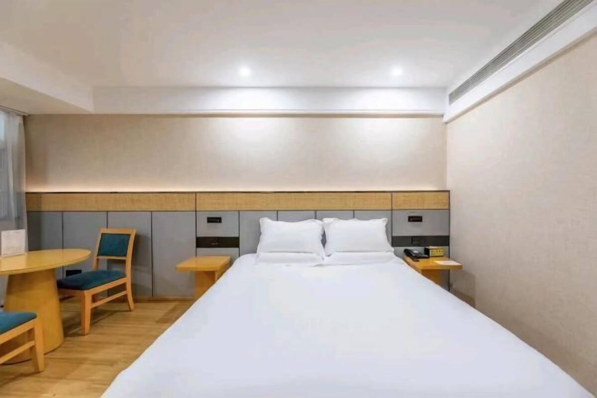 Ein Hotelzimmer mit einem großen Bett, einem Schreibtisch, einem Sessel und einem Nachttisch.