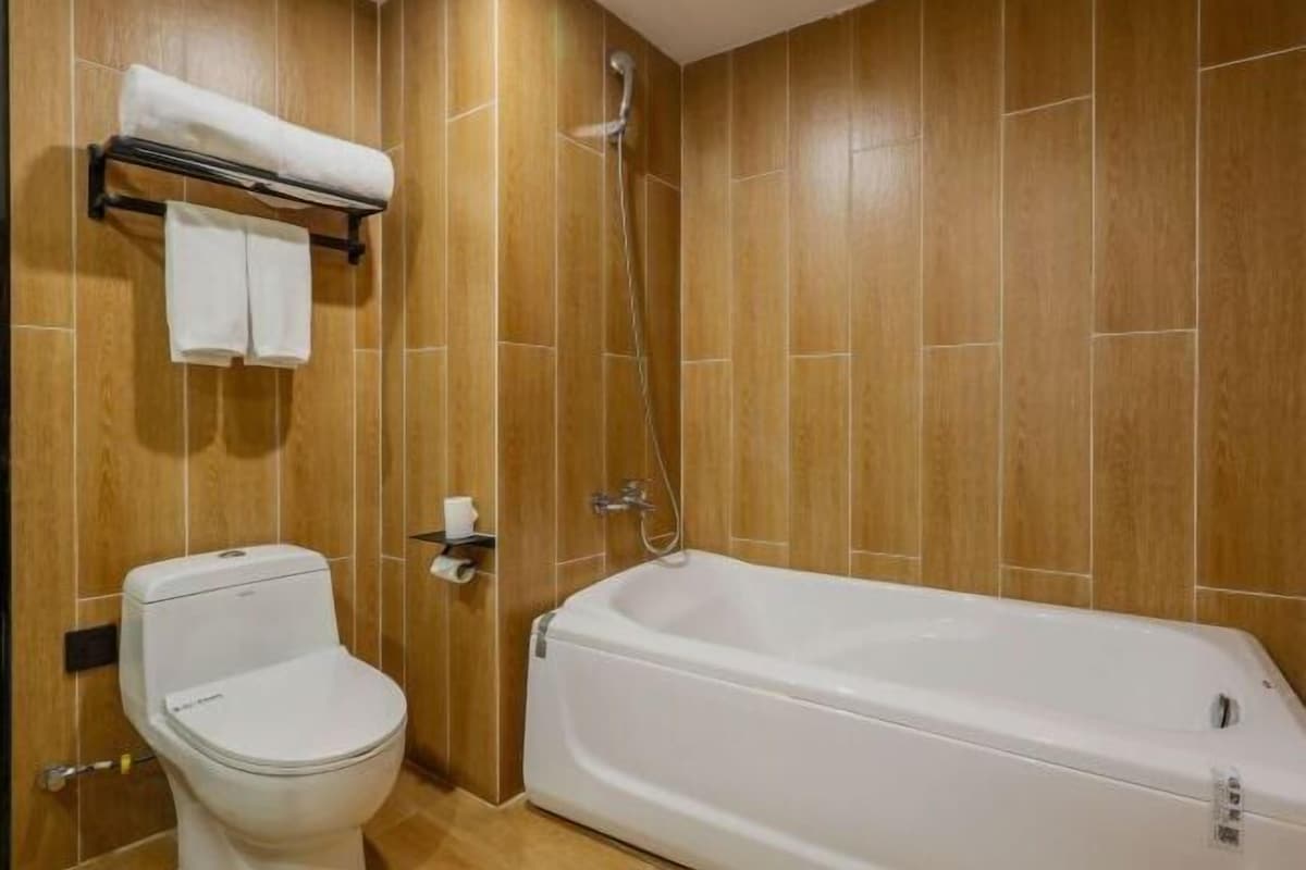 Een badkamer met een toilet, een bad en een handdoekhouder.