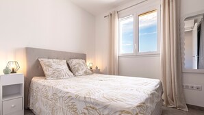 A bedroom with a bed, nightstands, a window, and curtains. - L'Île de Beauté - Climatisé (Pietrosella)