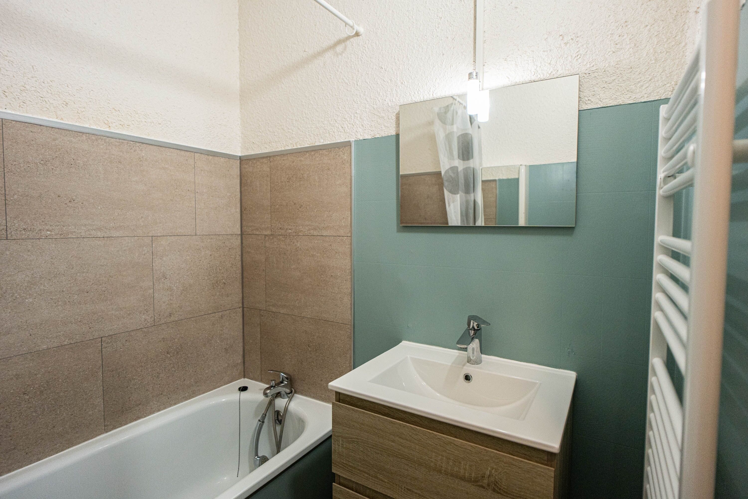 A bathroom with a bathtub, a sink, and a mirror.