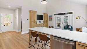 A modern kitchen with a large island, wooden cabinets, and a built-in TV.