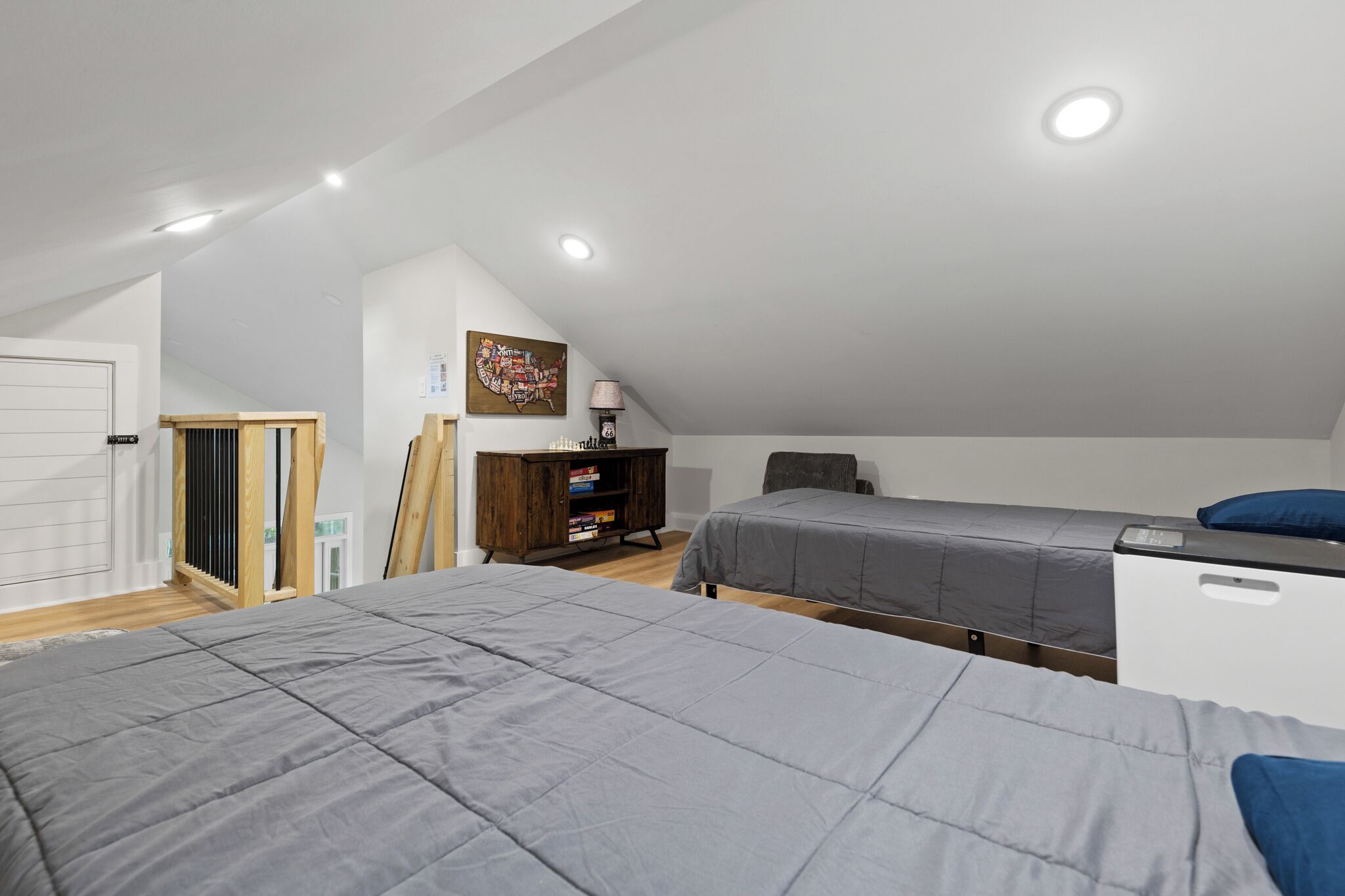 A bedroom with two beds, a wooden cabinet, a desk, and a chair.
