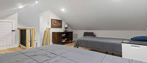 A bedroom with two beds, a wooden cabinet, a desk, and a chair.