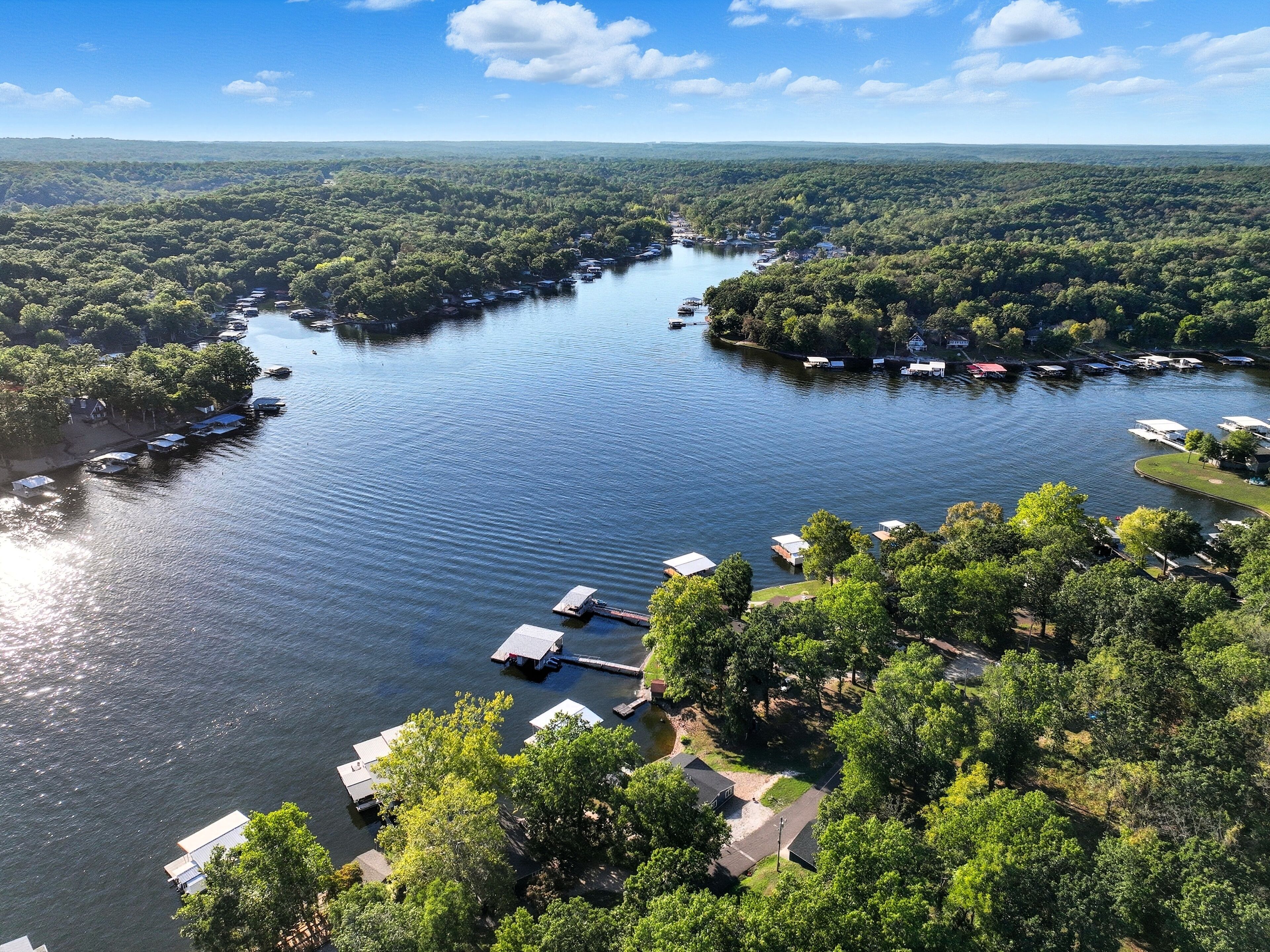 A river with boats docked along the banks, surrounded by dense forest.