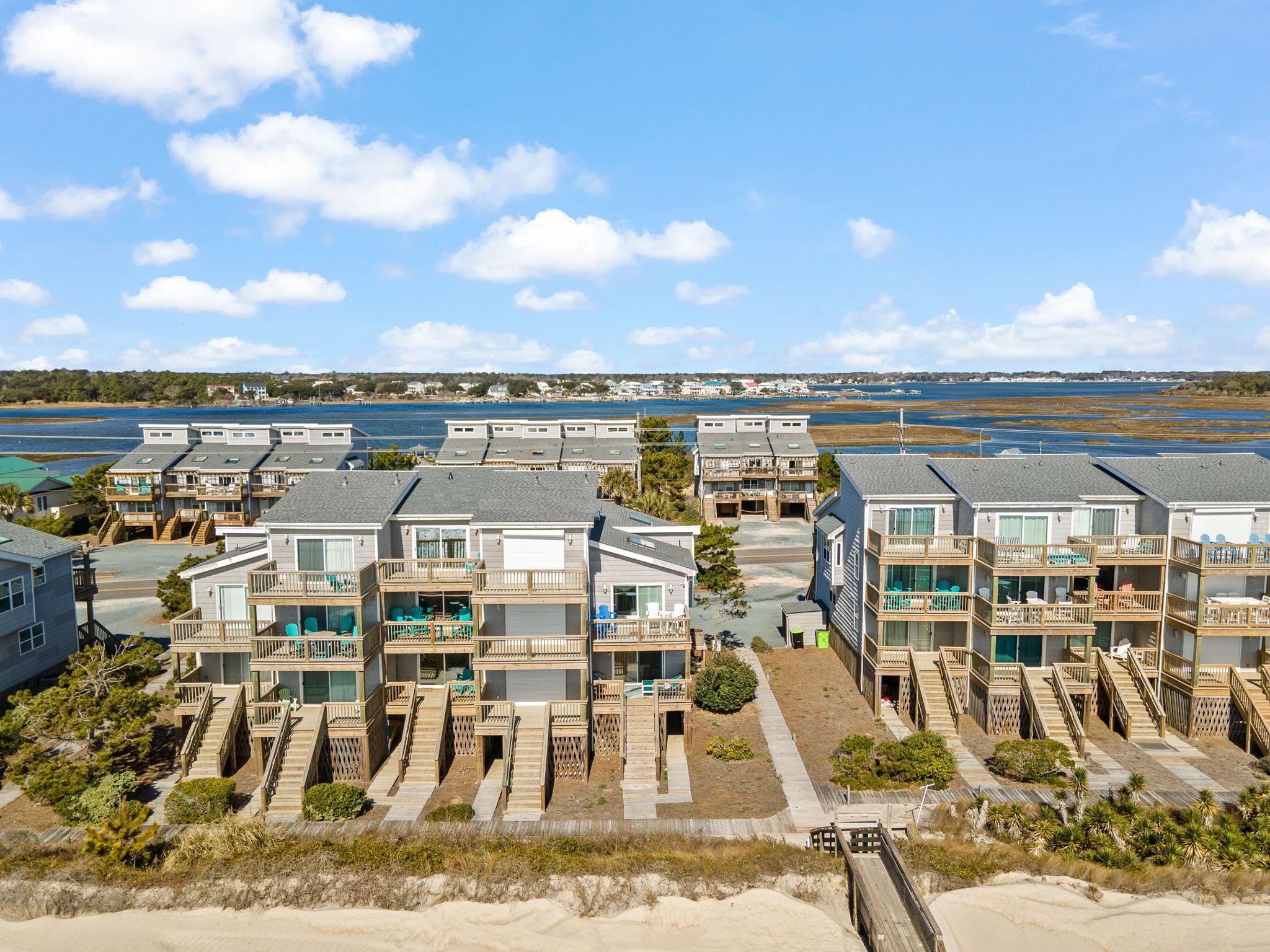 A beachfront property with multiple two-story buildings, each featuring balconies and direct access to sandy areas.