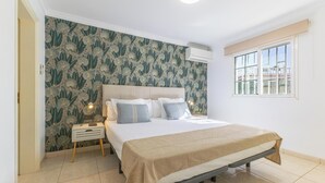 A bedroom with a bed, bedside tables, a window with a view, and a patterned wallpaper. - Careva Suites 21 by VillaGranCanaria (San Bartolomé de Tirajana)