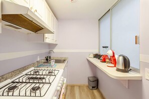 A compact kitchen with a gas stove, a sink, and a window overlooking a balcony. - Acogedor apartamento tipo boutique cerca d Reforma (Mexico City)