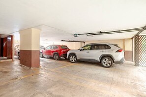 Een parkeergarage met twee geparkeerde auto's, betonnen vloeren en een metalen barrière aan de zijkant.