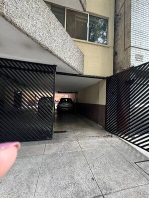 A parking garage with a car parked inside, a staircase leading to an upper level, and a gated entrance. - Acogedor apartamento tipo boutique cerca d Reforma (Mexico City)