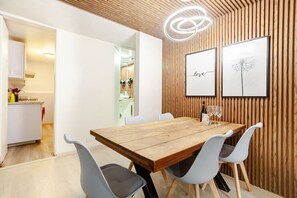 Ein Essbereich mit einem Holztisch, weißen Stühlen und gerahmten Bildern an der Wand.