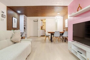 Een moderne woonkamer met een bank, eettafel, stoelen en een televisie.