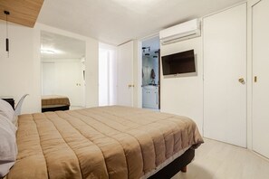A bedroom with a bed, a wardrobe, and a bathroom visible through an open door.