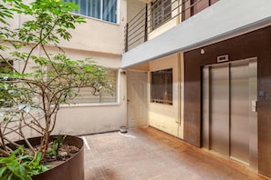 A narrow courtyard with a potted plant, a door, and an elevator.