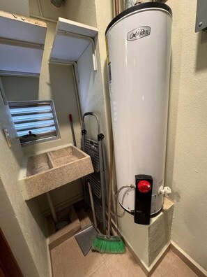 A bathroom with a white water heater, a small sink, and a broom. - Duplex 3BR con terraza y parking I Roma Sur (Mexico City)