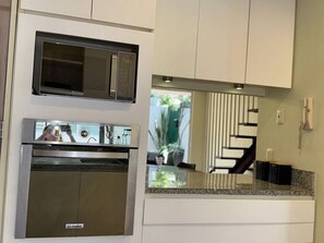 A kitchen with a microwave, oven, and a glass-top counter.