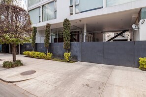 A modern building with a concrete facade, a covered entrance, and a staircase leading to an upper level.