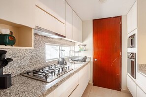 A compact kitchen with a gas stove, a microwave, and a built-in oven. - Duplex 3BR con terraza y parking I Roma Sur (Mexico City)