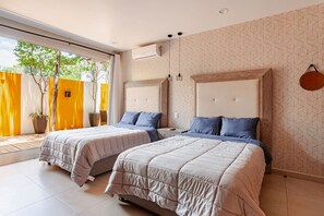 A modern bedroom with two beds, a large window, and a geometric patterned wall.