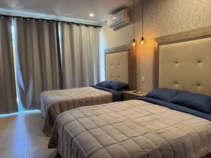 Een hotelkamer met twee bedden, een nachtkastje, een wandairconditioner en een behang met patroon.