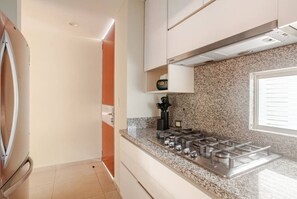 A modern kitchen with a stainless steel stove, granite countertop, and a window with blinds.