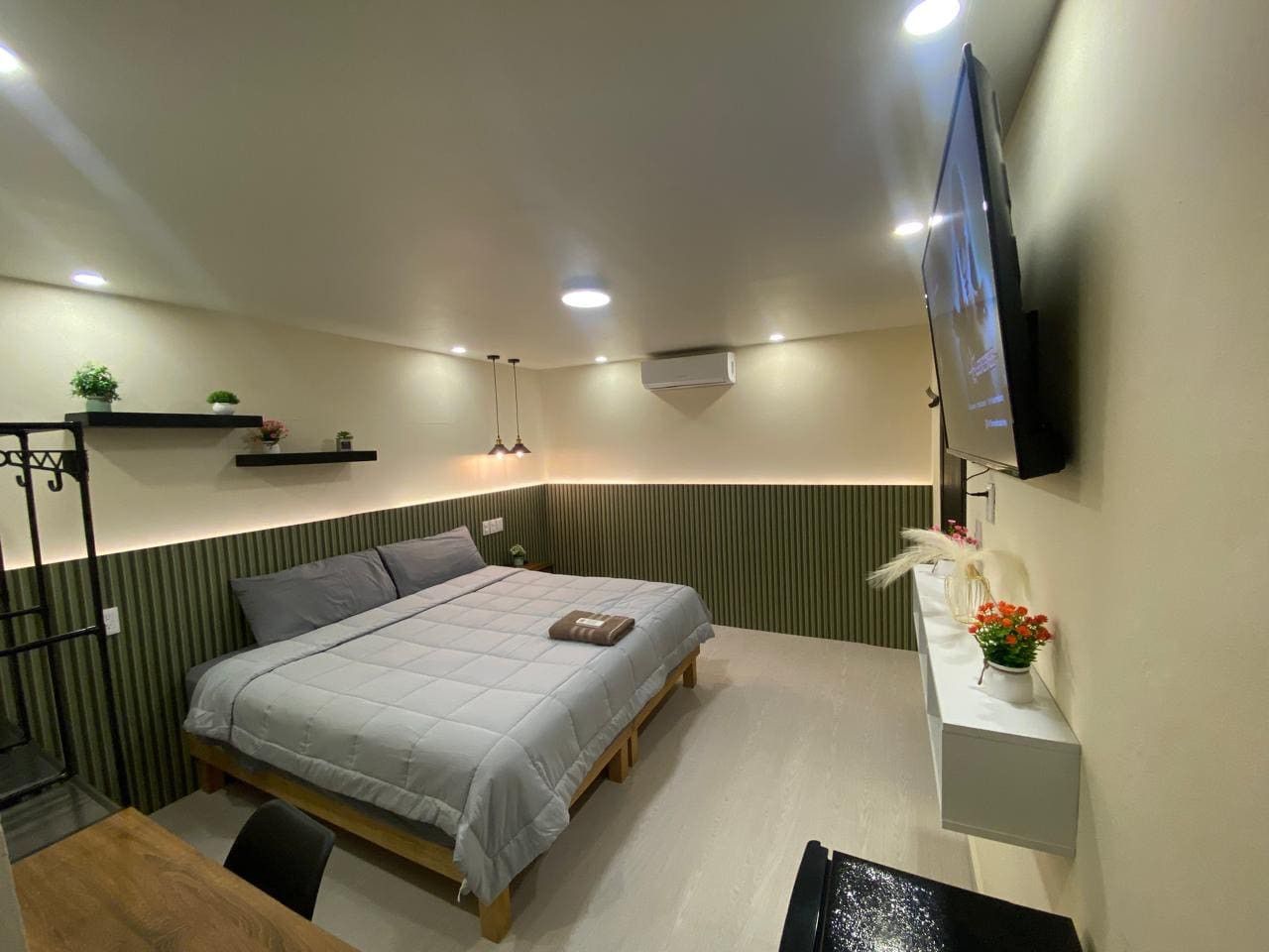 A modern bedroom with a bed, bedside table, and a mounted TV.