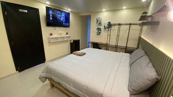 A bedroom with a bed, a TV mounted on the wall, a shelf with items, and a door labeled "Mr. Pumper."