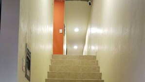 En trappa med beige kakelplattor som leder upp till en orange dörr längst upp.