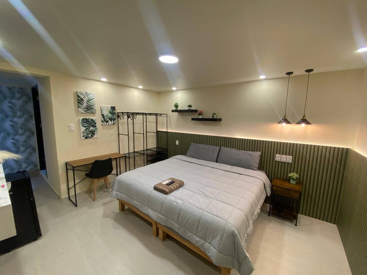 A bedroom with a bed, bedside table, and a desk with a chair.