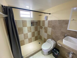 A bathroom with a shower, toilet, and sink. - Mini Hotel Chetumal – Habitación 4 · Cama King (Chetumal)