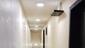 En smal hall med kakelgolv och beige väggar.
