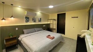 Un dormitorio con cama, mesitas de noche, aire acondicionado, armario y televisor.