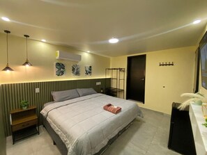 Een slaapkamer met een bed, nachtkastjes, een airconditioning, een kledingkast en een televisie.