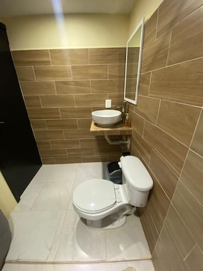 A small bathroom with a toilet, sink, and mirror. - Mini Hotel Chetumal – Habitación 2 · Cama King (Chetumal)