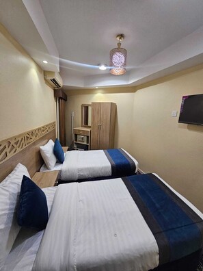 A hotel room with two beds, a wardrobe, a TV, and a decorative ceiling light.