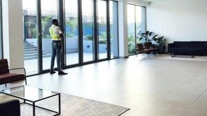 Un hall d’entrée spacieux, doté de grandes fenêtres, d’un espace salon et d’une personne se tenant près des fenêtres.