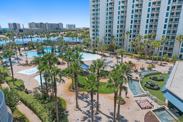 A resort with multiple swimming pools, palm trees, and a large building with balconies. - Palms Resort #1603 Jr. 2BR (Destin)