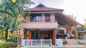 A two-story house with a balcony, a swimming pool, and a covered patio area. - Peaceful Resort-Style pool villa in Doi Saket, Chiang Mai (Tambon Choeng Doi)