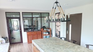 A modern kitchen with a marble countertop, wooden cabinets, and a hanging light fixture. - Peaceful Resort-Style pool villa in Doi Saket, Chiang Mai (Tambon Choeng Doi)