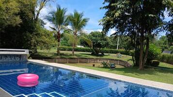 A swimming pool with a pink float, surrounded by lush greenery and palm trees.