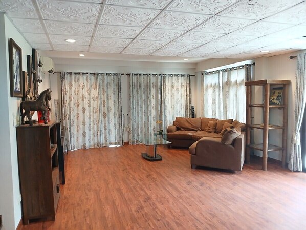 A living room with a brown sofa, a glass coffee table, and patterned curtains. - Peaceful Resort-Style pool villa in Doi Saket, Chiang Mai (Tambon Choeng Doi)