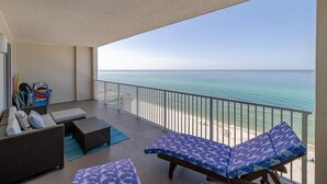 A balcony with a view of the ocean, wicker furniture, and a surfboard rack. - Ocean Reef 1105 (Panama City Beach)