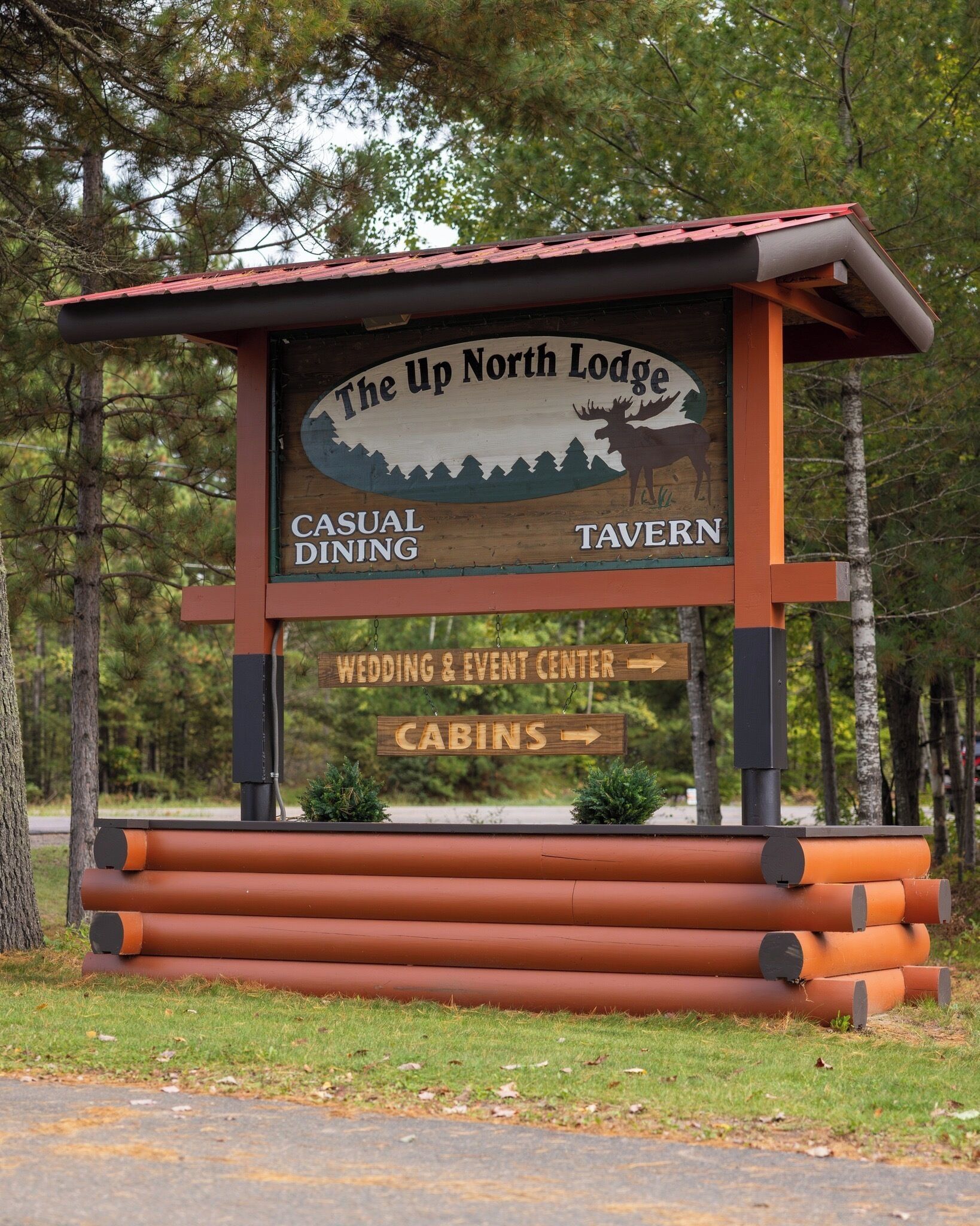 A wooden signboard for The Up North Lodge with amenities like casual dining, tavern, wedding & event center, and cabins.