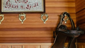 Un panneau encadré portant l’inscription « Que Dieu bénisse ce foyer » et un violon accroché à un mur en bois.