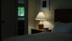 A hotel room with a bed, a bedside table with a lamp and an alarm clock, a framed picture on the wall, and a door leading to a balcony. - Warren Village home steps from bubbling brook (Warren)